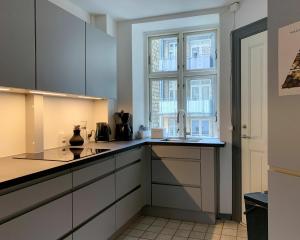 哥本哈根ApartmentInCopenhagen Apartment 720的厨房配有白色橱柜和窗户。