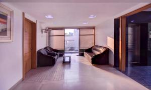 奥兰加巴德Treebo Trend Admiral Suites New Usmanpura的走廊设有两张皮椅和一张桌子