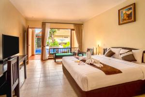 罗威那New Sunari Lovina Beach Resort的酒店客房设有一张大床和一台电视。