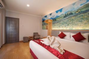 Labu SumbawaKaloka Airport Hotel的卧室配有一张床,墙上挂有绘画作品