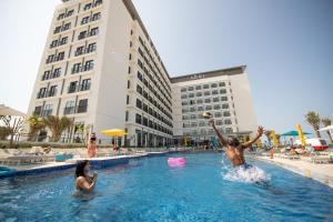 迪拜Rove La Mer Beach, Jumeirah的两人在酒店游泳池玩耍