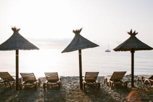 林古泽塔Domaine Naturiste de Riva Bella的海滩上的一组椅子和遮阳伞