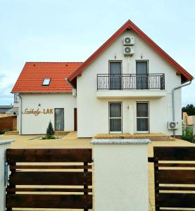海吉克Székely-Lak Apartman Hegykő的前面有木栅栏的白色房子