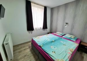 索普隆索普隆玛丽卡公寓的一间小卧室,配有一张带蓝色床单的床和窗户