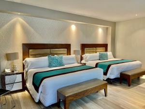 瓜达拉哈拉金叶酒店及套房 的酒店客房 - 带两张带蓝色枕头的床