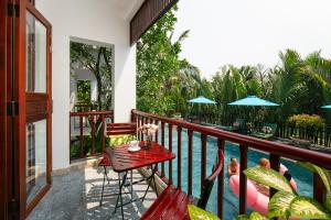 会安Hoi An Riverside Villas & Apartments的游泳池畔阳台配有桌椅