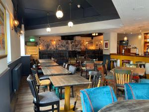 曼彻斯特Piccadilly Central的一间带木桌椅的餐厅和一间酒吧