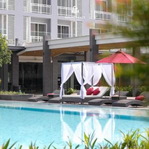 罗勇Golden City Rayong Hotel - SHA Extra Plus Certified的一座带椅子和遮阳伞的游泳池位于一座建筑旁边