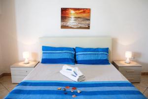卡斯特里尼亚诺德尔卡波Complesso Centopietre by TerraSalento的一间卧室配有一张带蓝色床单的床和两盏灯。