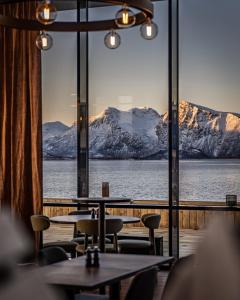苏特兰Scandic Sortland的餐厅设有桌子,享有雪覆盖的山脉美景