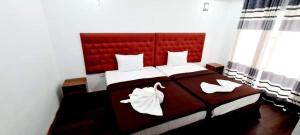 努沃勒埃利耶Nive Inn的一间卧室配有一张大床和红色床头板