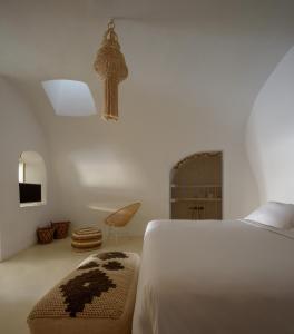 费拉圣托里尼之家别墅的一间卧室配有一张床、一把椅子和电视