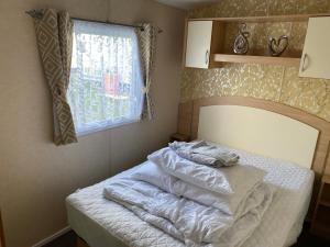 塔特舍尔3 bedroom 8 berth Standard Basic caravans with Hot Tub,Mountain Bikes的一间卧室配有一张带白色床单的床和一扇窗户。