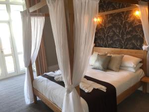 尚克林遮阳旅馆的卧室配有带白色窗帘的天蓬床