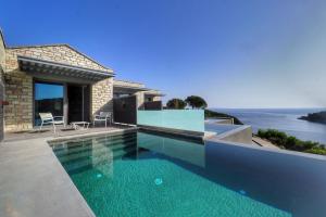 塞沃塔多莫特贴水尼古拉斯套房度假酒店的一座位于大海房子前面的游泳池