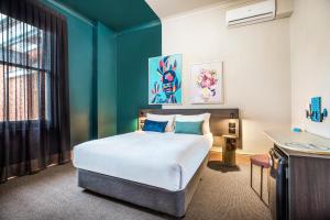 阿德莱德Ramsgate Hotel by Nightcap Social的一间卧室设有一张床和蓝色的墙壁