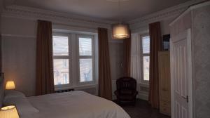 邓弗里斯Lindean Guest House的一间卧室配有一张床、一把椅子和窗户。
