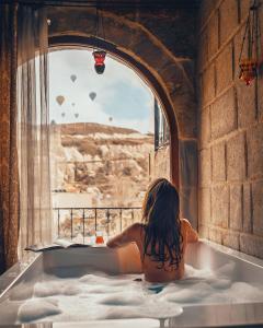 格雷梅天使洞穴套房酒店的坐在浴缸里,看着窗外的小女孩
