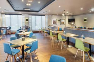 彼得伯勒假日彼得伯勒西区酒店的餐厅设有木桌和蓝色椅子