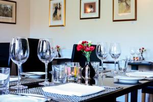 什鲁顿Rollestone Manor B&B and Restaurant的酒杯桌子和红花花瓶