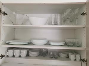 Paralía AvdhíronАпартаменти Анджело的装满盘子、碗和玻璃杯的白色橱柜