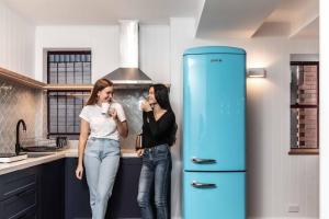 悉尼Perouse Randwick by Sydney Lodges的两名妇女站在一个蓝色冰箱旁边的厨房里