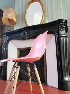 纳博讷Les Chambres des Barques的壁炉前的粉红色椅子