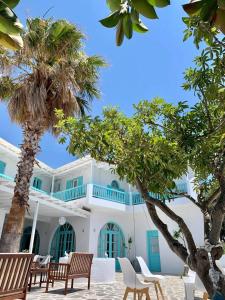 艾丽奇Aliki Panorama Rooms的白色的建筑,拥有蓝色的窗户和棕榈树