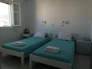 艾丽奇Aliki Panorama Rooms的白色客房内的两张床和毛巾