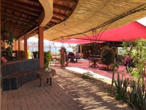 塔斯科·德·阿拉尔孔Hotel SPA Campestre Los Adobes的一个带长凳和红色遮阳伞的庭院