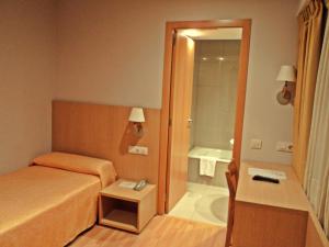 圣地亚哥－德孔波斯特拉温莎酒店的一间卧室配有一张床,浴室设有浴缸