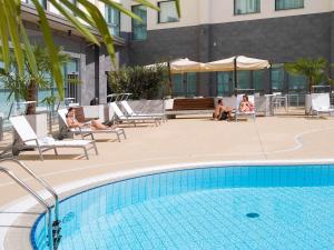 卡尔达诺阿尔坎波诺富特米兰马尔彭萨机场酒店的两人坐在游泳池旁的椅子上