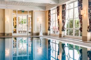 巴登韦勒Relais & Châteaux Hotel Schwarzmatt的酒店大堂的游泳池,设有窗户