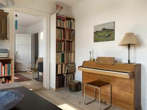 哥本哈根ApartmentInCopenhagen Apartment 1454的客厅配有钢琴和书架