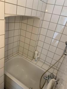 哥本哈根ApartmentInCopenhagen Apartment 1454的一间铺有白色瓷砖并带浴缸的浴室。