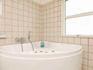 海尔斯8 person holiday home in Hals的瓷砖浴室设有白色浴缸,浴室设有窗户