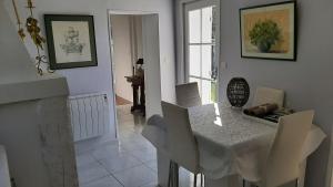 圣洛朗－德塞尔当maison en pierre dans un écrin de verdure的一间配备有白色桌椅的用餐室
