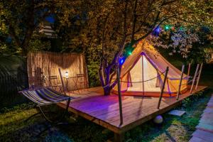 布拉索夫Dragonfly Gardens Urban Glamping Brasov的木制甲板上的帐篷和吊床