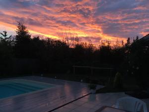 勒泰克Le Teich Tranquille的庭院中游泳池的日落