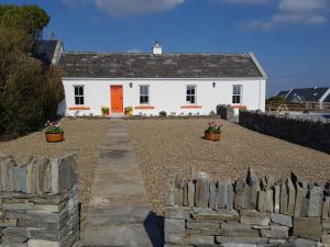 杜林The Coral Cottage的一座白色的房子,设有橙色的门和石墙