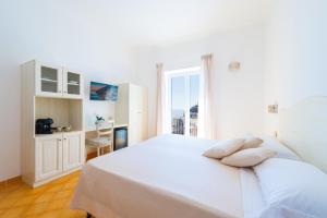 波西塔诺Casa Pietro的白色的卧室设有白色的床和窗户。