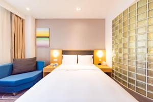 石家庄石家庄和平智选假日酒店的酒店客房设有一张大床和一张蓝色的沙发。