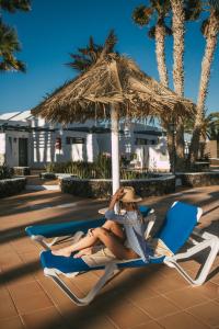 卡门港蓝色海洋海滩公寓式酒店的坐在海滩椅上,在伞下坐的女人