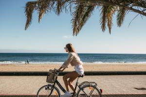 卡门港蓝色海洋海滩公寓式酒店的一名妇女在海滩上骑着自行车