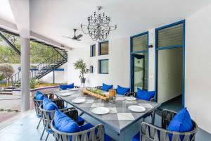 班加罗尔StayVista at Ananta的一间带长桌和蓝色椅子的用餐室