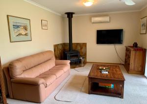 金斯科特Leeward 'tranquil beachfront'的带沙发和燃木炉的客厅