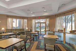 好莱坞劳德代尔堡机场拉昆塔酒店的餐厅设有桌椅和窗户。