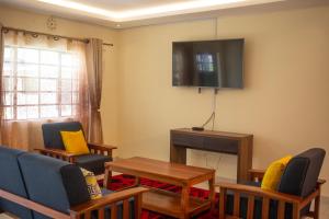 洛德瓦尔Lodwar Acacia Residences的客厅配有椅子和墙上的电视