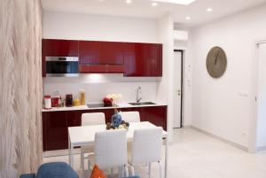 那不勒斯Napoli City Center - Appartamenti e Camere的厨房配有红色橱柜和白色的桌椅