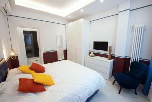 那不勒斯Napoli City Center - Appartamenti e Camere的一间卧室配有一张床、一把椅子和电视